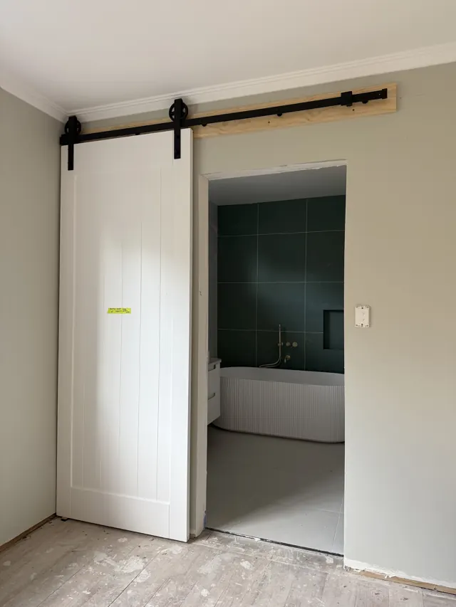 White sliding barn door on a black track opening onto a bathroom