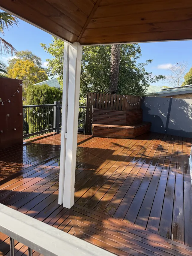 Freshly oiled timber deck under a white pergola