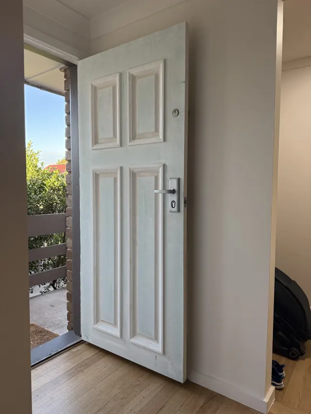White panelled front door newly hung with a lever handle and deadbolt